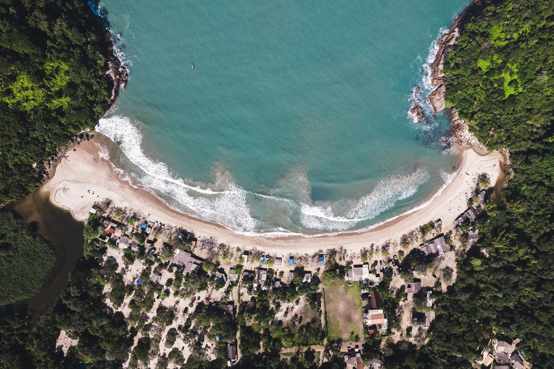 Vista aérea de drone de uma enseada com mar verde e mata atlântica
